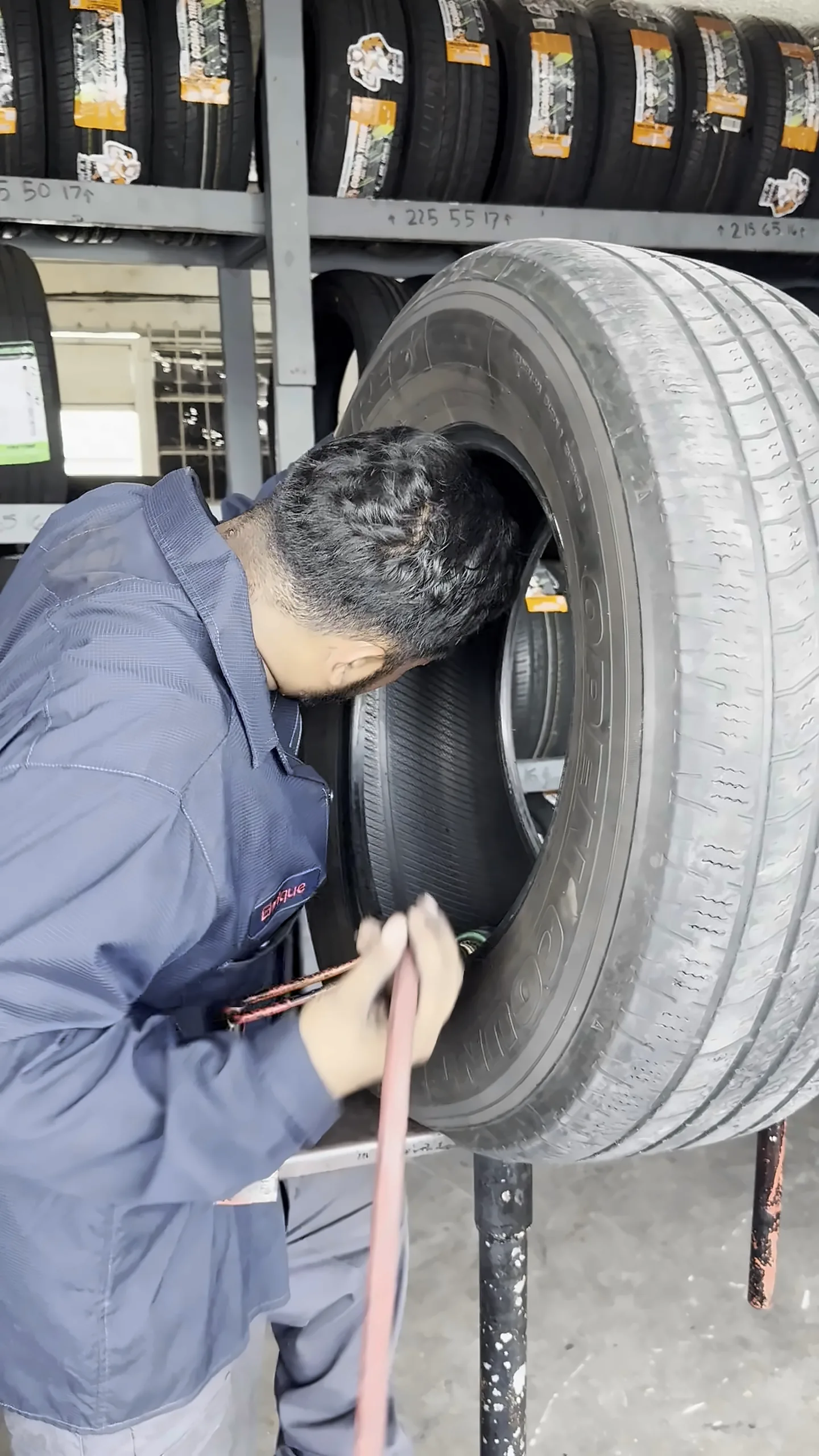 Técnico revisando el interior de una llanta frente al estante de llantas